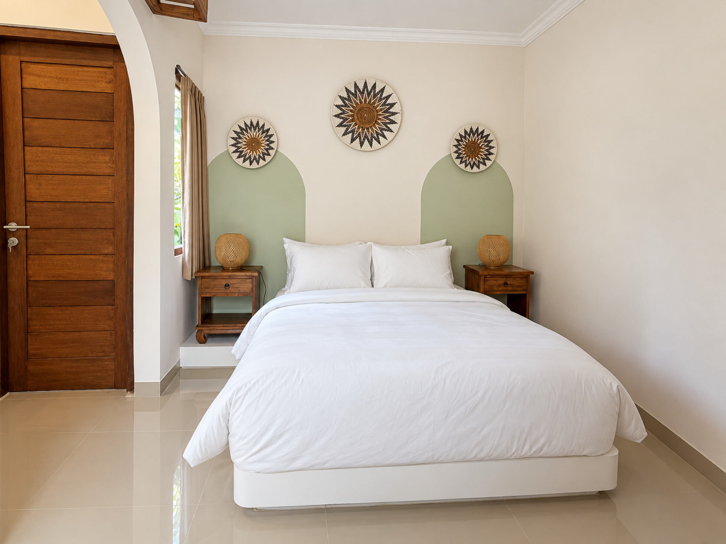 Double bed with white linens, woven lamps and green wall accents