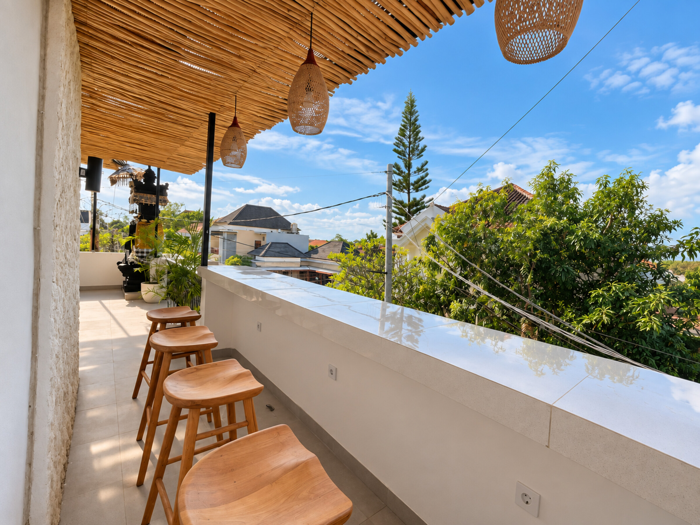Wooden stools along a covered balcony overlooking trees and nearby rooftops