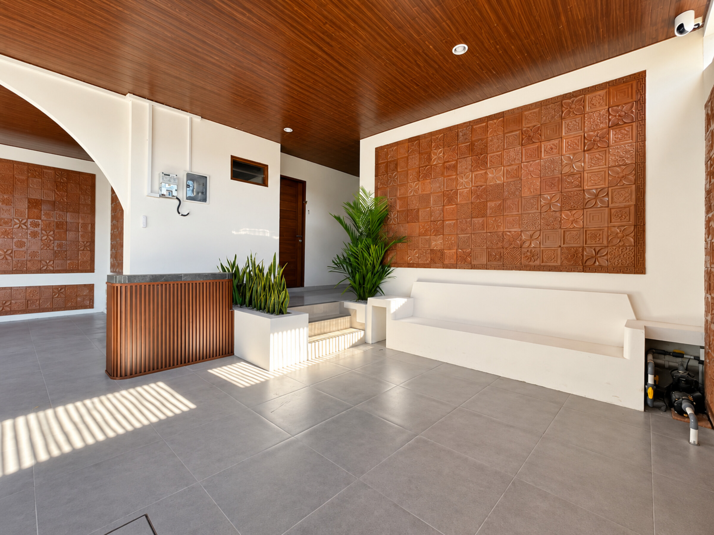 Reception desk and white bench beneath decorative terracotta wall panels