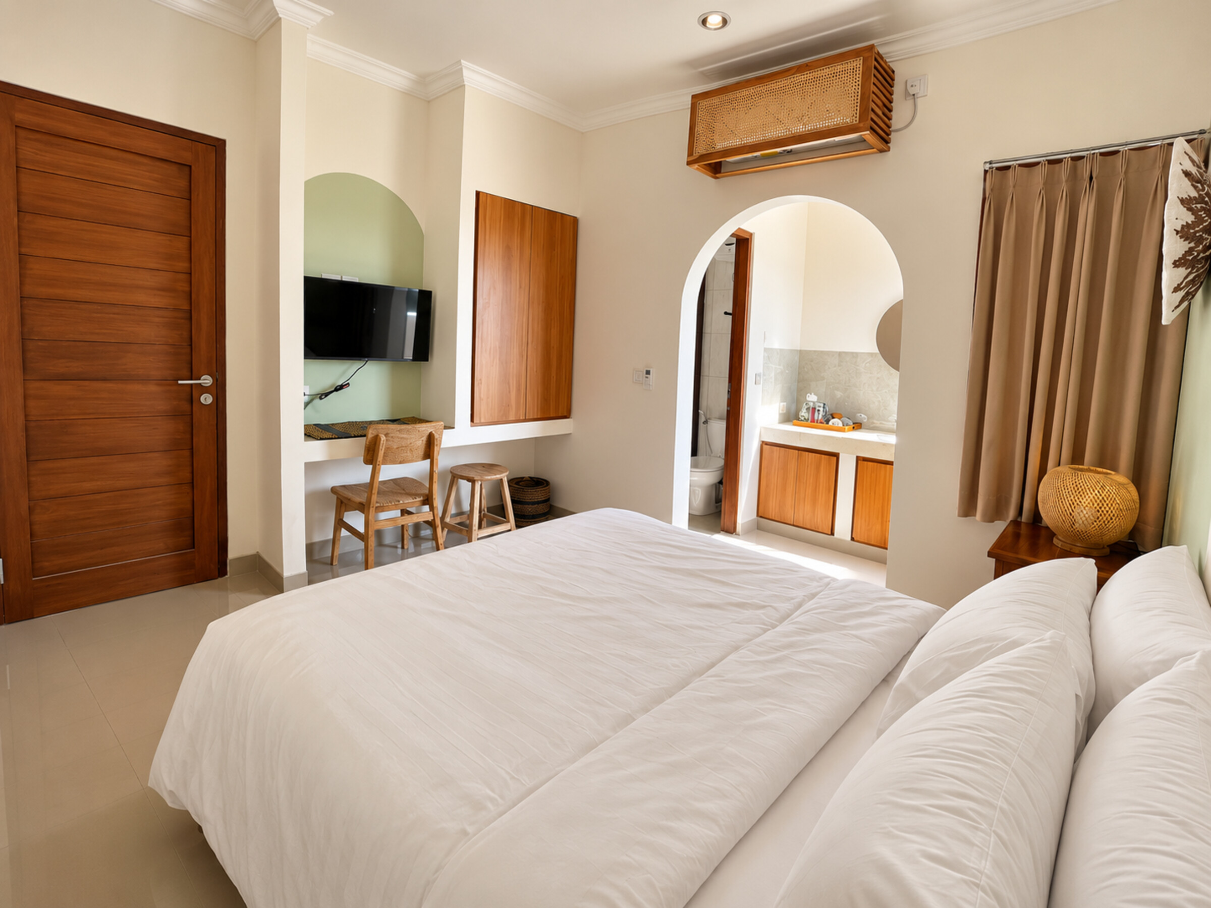 Guest room with a double bed, television, desk and arched vanity entrance